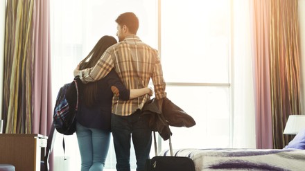 Loving young couple looking through window in hotel room