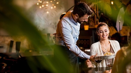 Kellnerin bringt Speisen an den Tisch