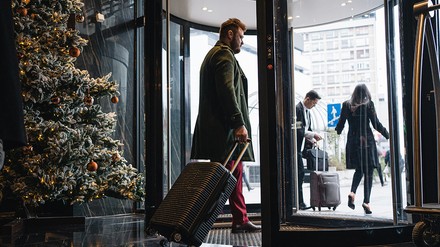 Pärchen verlässt ein Hotel mit Weihnachtsbaum durch die Drehtür