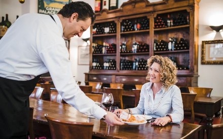 Ein Kellner serviert einer Dame ein Gericht