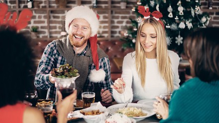 Gruppe sitzt am bestückten Tisch im Restaurant und feiert Weihnachten