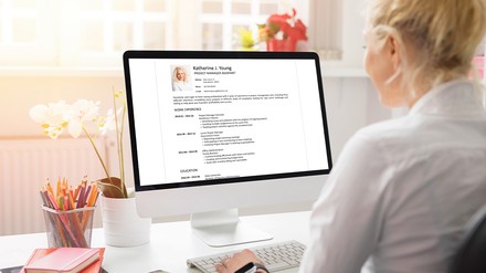 Blonde Frau sitzt am PC und bearbeitet ihren Lebenslauf online