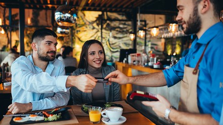 Kellner kassiert Gäste ab