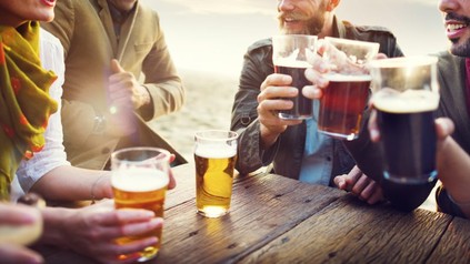 Gruppe sitzt an Tisch und trinkt Bier