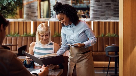 Kellnerin zeigt einem Gast etwas auf der Speisekarte
