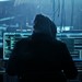 Ein Hacker sitz vor Computerbildschirmen.