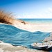 Handtuch, Flip-Flops und Sonnenhut am Sandstrand