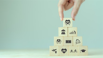 Turm aus Holzwürfeln, auf denen symbolisch Mitarbeiter-Benefits abgebildet sind