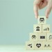 Turm aus Holzwürfeln, auf denen symbolisch Mitarbeiter-Benefits abgebildet sind