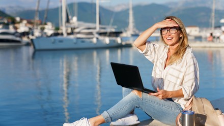 Frau arbeitet mit Laptop am Yachthafen