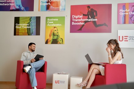 Zwei Studenten sitzen mit Laptop und Tablet auf zwei Sesseln