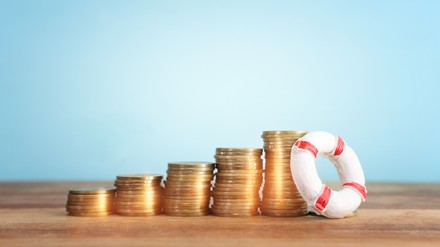 concept image of stacked coins and life bouy over wooden background. banking, funds and assistance idea