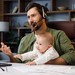 Junger Mann mit Kind auf dem Schoß während eines beruflichen Video-Calls