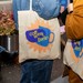 Zwei Menschen mit Coffee Week Jutebeuteln