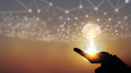 Hand vor Sonnenuntergang hält virtuelle Glühbirne