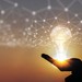Hand vor Sonnenuntergang hält virtuelle Glühbirne