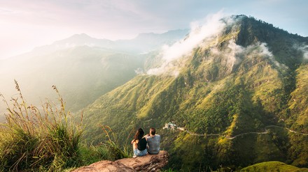 Zwei Urlauber sitzen in der Natur und schauen in die Ferne in die Berge