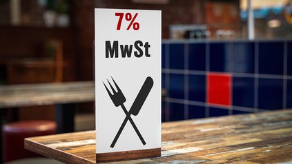 Ein Schild mit Messer und Gabel in einem Restaurant mit Aufschrift: 7 Prozent MwSt.