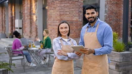 Mitarbeiter im Servicebereich vor einem Restaurant mit Tablet