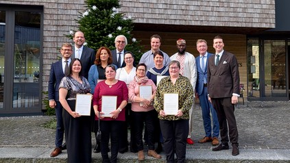 Gruppenfoto der Jubilare und Hotelleitung vor der Traube Tonbach in Baiersbronn; mehrere Mitarbeiter halten Urkunden, im Hintergrund steht ein geschmückter Tannenbaum.