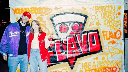 Zwei Gäste vor einer Flavo-Graffitiwand bei der Premiere der American Style Pizza-Brand in Berlin.