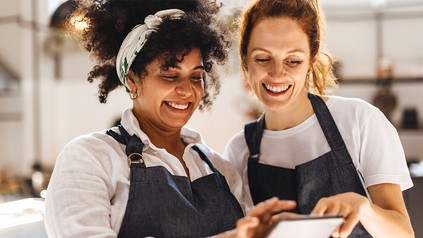 Zwei Mitarbeiter im Gastgewerbe schauen lächelnd auf ein Tablet