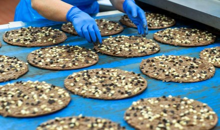 Ein Mitarbeiter am Fließband kontrolliert die Dr. Oetker Schokoladenpizzen