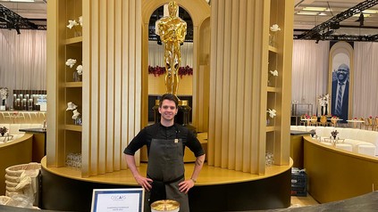 Bernhard Zimmerl steht in der Oscar-Küche in Los Angeles vor einer goldenen Oscar-Statue beim Governors Ball.