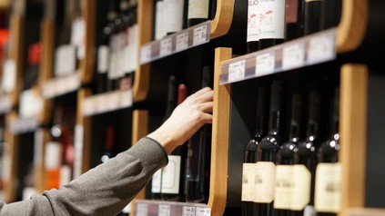 Eine Hand greift in ein Weinregal