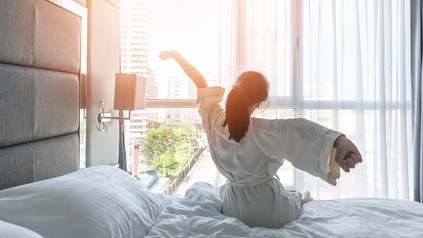 Hotel room comfort with good sleep easy relaxation lifestyle of Asian girl on bed have a nice day morning waking up, taking some rest, lazily relaxing in guest bedroom in city hotel