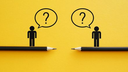 Zwei Personen stehen sich mit Fragezeichen zwischen ihnen gegenüber – Symbolbild für Wissensverlust und fehlenden Wissenstransfer im Unternehmen