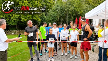Teilnehmer stehen beim gastRUNomie-Lauf 2025 in Köln an der Startlinie, während ein Moderator den Start begleitet