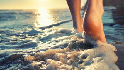 Nackte Füße die am Strand entlang wandern