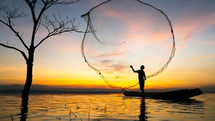 Person wirft Fischernetz aus