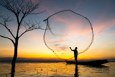 Person wirft Fischernetz aus