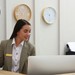 Rezeptionistin mit Telefonhörer in der Hand schaut auf ihren Computer