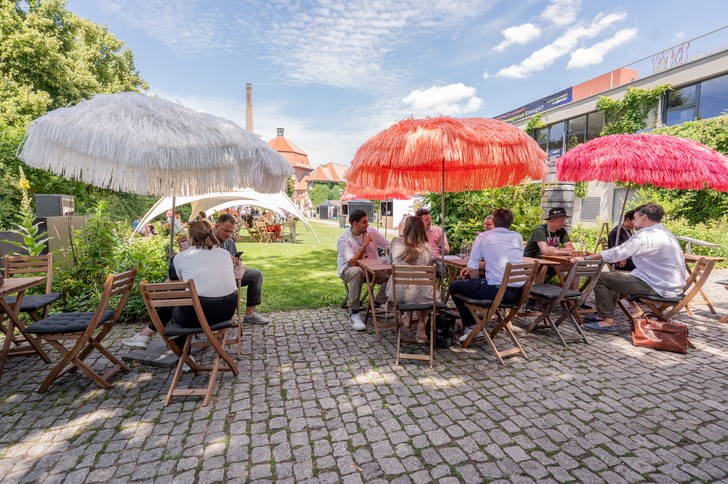 Teilnehmer des UPNXT Hospitality Festivals 2026 tauschen sich auf der Außenfläche der Veranstaltungslocation in Berlin in lockerer Festivalatmosphäre aus.