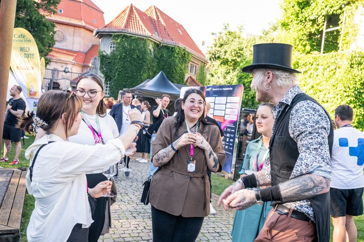 Teilnehmer des UPNXT Hospitality Festivals 2026 tauschen sich auf der Außenfläche der Veranstaltungslocation in Berlin in lockerer Festivalatmosphäre aus.