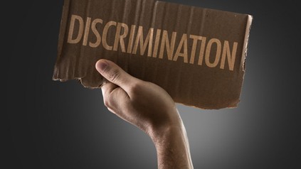 Mann hält Pappe mit Inschrift "Discrimination"