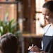 Servicekraft nimmt in einem Restaurant die Bestellung eines Gästepaares auf.