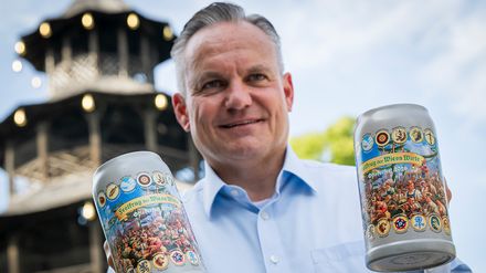 Christian Scharpf hält zwei offizielle Wirtekrüge für das Oktoberfest 2026 vor dem Chinesischen Turm in München