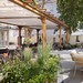 Außenbereich des Hotels Imperial Riding School in Wien mit begrünten Sitzplätzen, großen Bäumen und einer Bar.