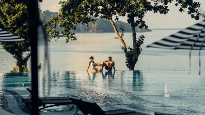 Ein Pärchen sitz am Rand eines Infinity-Pools