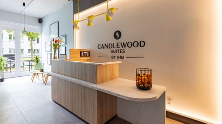 Rezeption des Candlewood Suites Berlin Airport mit Empfangstresen und Markenlogo an der Wand.