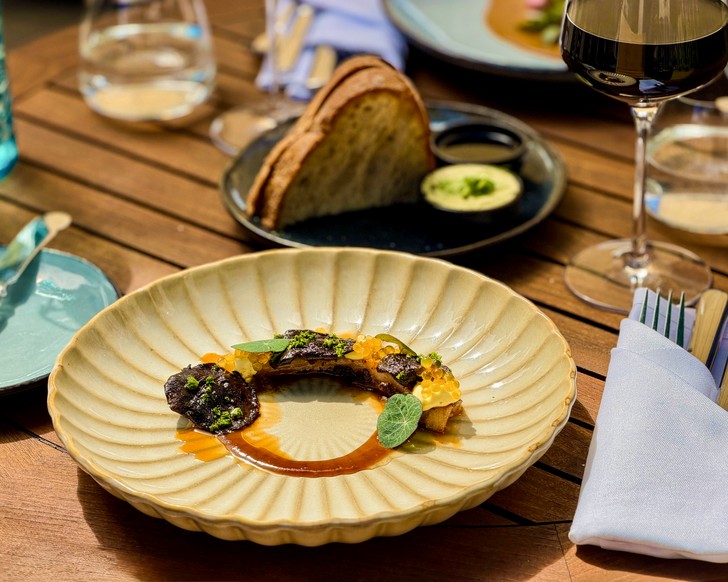 Gericht aus dem saisonalen Menü der ElbUferei Restaurant & Bar mit Brot und Rotwein.