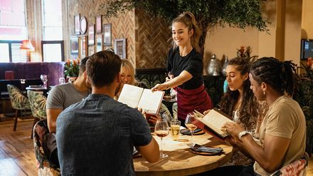 Servicekraft bringt Speisen an den Tisch