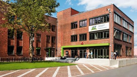 Backsteingebäude der IST-Hochschule mit Studenten vor dem Eingang