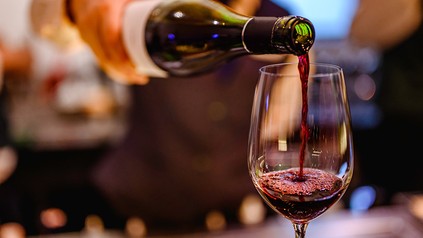 Mensch schenktWein in Glas ein