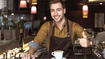 Kellner am Tresen zeigt Daumen hoch