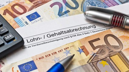 Euroscheine und Zettel mit Inschrift "Gehaltsabrechnung"